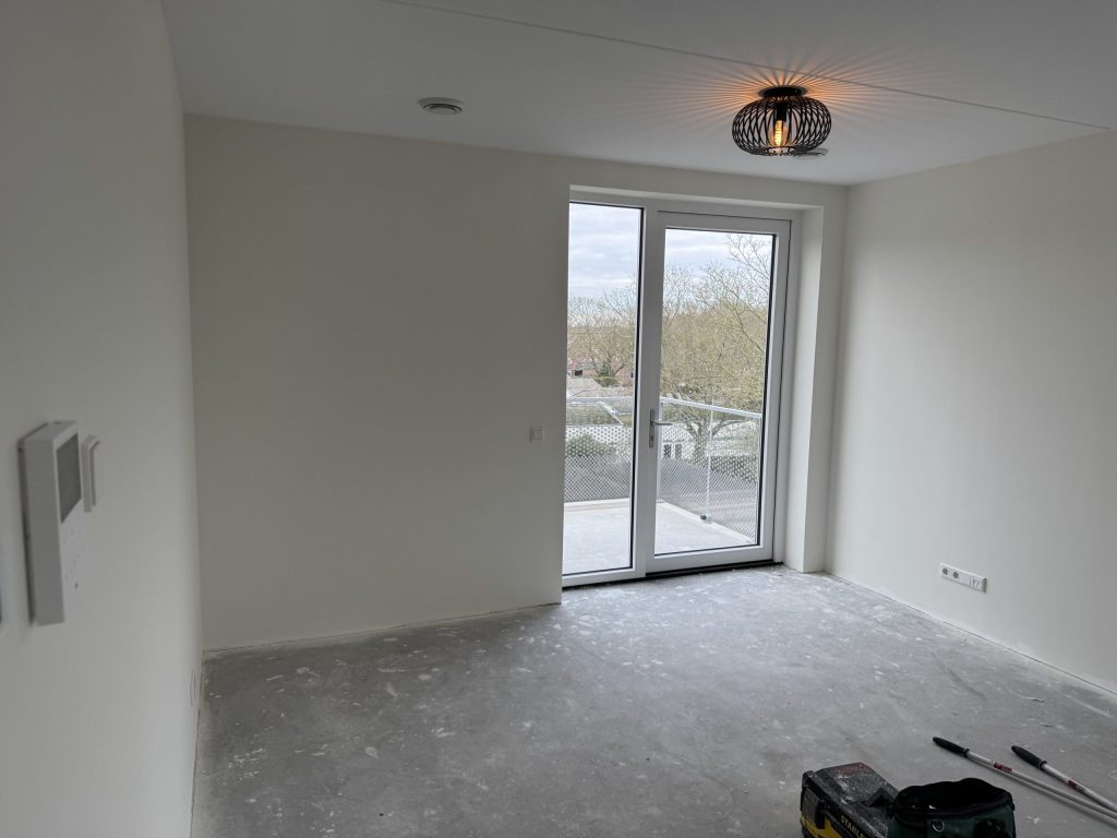Lege kamer met balkondeuren en witte wanden, klaar voor de behanger